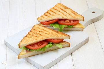 Sandwich with tomatoes, cheese and ham on a white background