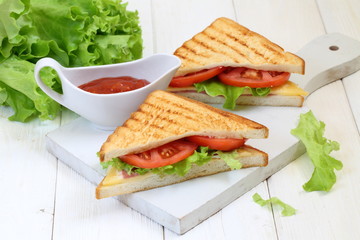 Sandwich with tomatoes, cheese and ham on a white background