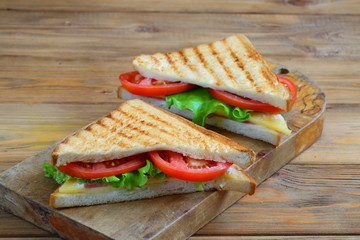Sandwich with tomatoes, cheese and ham on a dark, wooden background