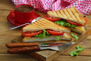 Sandwich with tomatoes, cheese and ham on a dark, wooden background