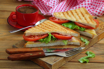 Sandwich with tomatoes, cheese and ham on a dark, wooden background