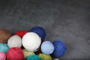 A lot of multi-colored yarn balls on the dark background. Knitting yarn close-up. Knitting is...