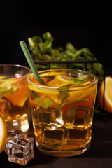 Fresh cocktail Cuba Libre with brown rum, cola, mint and lime on black background. Long Island Iced Tea cocktail.