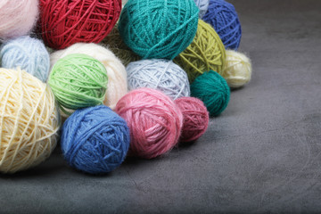 A lot of multi-colored yarn balls on the dark background. Knitting yarn close-up. Knitting is...