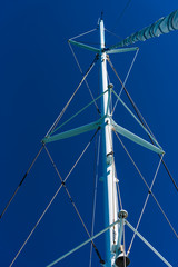 detail of tall ship mast of sailing boat with rigging on blue background
