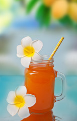 Glass of tropical exotic multifruit juice cocktail drink with Plumeria frangipani flower for decoration.