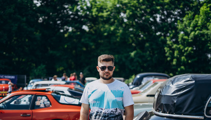 Handsome man in sunglasses near retro cars.