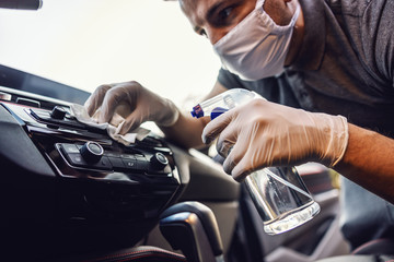 Man in protective suit with mask disinfecting inside car, wipe clean surfaces that are frequently touched, prevent infection of -covid 19 virus ,contamination of germs or bacteria. Infection.