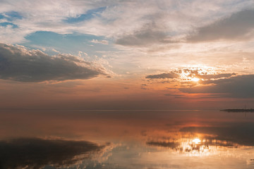 Sunset in the clouds over the water in calm