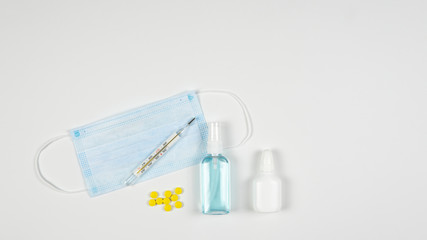 Protective medicine mask, antiseptic, thermometer and pills, flat lay