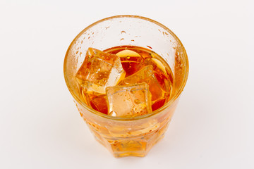 Glass of scotch whiskey and ice over white background.