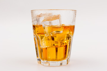 Glass of scotch whiskey and ice over white background.