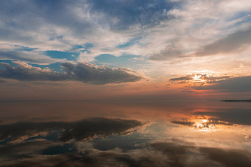 Fototapeta na wymiar Sunset in the clouds over the water in calm