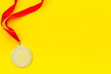 Gold medal with red ribbon - winner, success concept - on yellow background top view copy space