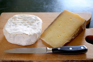 two different seasoned cheese rest on a wooden board with copy space for your text