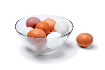 eggs of different colors from white to brown in a glass bowl and another one near, isolated on a white background