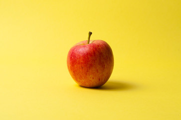 One red apple on a yellow background. The concept of ideas, weight loss and proper nutrition