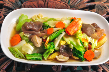 Stir fried mixed vegetables in a white plate on a wooden table