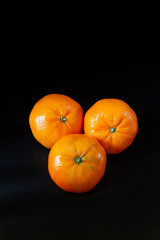 Three tangerines clementines on black background