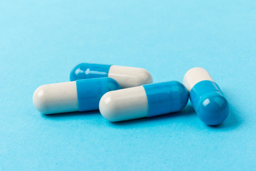 Pills isolated on blue background. Medical drug capsule. Concept of coronavirus
