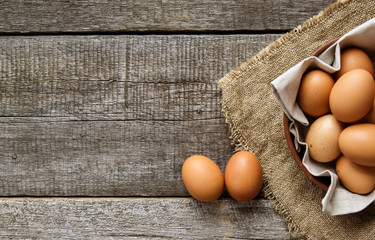 Chicken eggs in a clay plate with a linen napkin and two eggs on burlap. View from above. Copy space.
