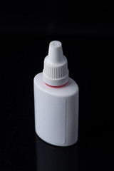 White plastic medical container on white, black background..nasal spray
