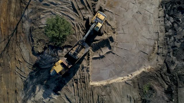 Aerial top down shot of an excavator loading dirt on the truck