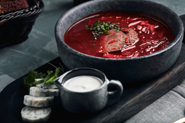 Hot soup. Borsch with red beans and braised beef. Comfortable food. Serving with brown bread and pork fat in a rustic style.