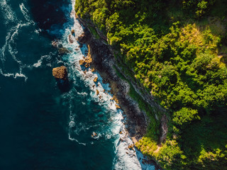 Aerial view of cliff and ocean with waves in Bali.
