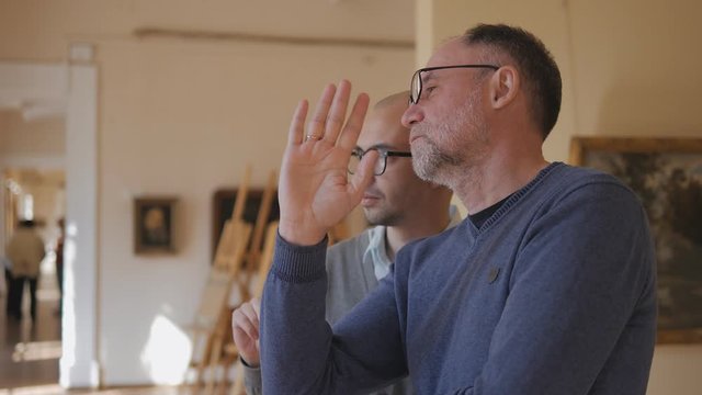 Two intelligent men in the Museum look at the exhibit, and talk about art