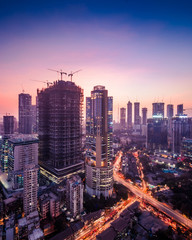 Twilight view of the Mumbai cityscape in purple hues showing a lot of under construction and existing residential and commercial skyscrapers and highrises.