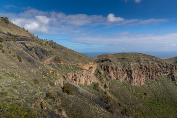 Fototapeta na wymiar View of the mountainous landscape of volcanic origin along with lots of trees and vegetation and on the horizon, you can see the setting moon Gran Canary island