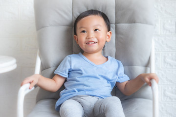 Adorable little boy sitting on big chair isolated,Smiling little boy sitting on stool.The little boy is lying.On a chair