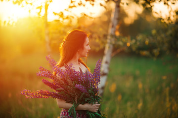 outdoor portrait of a beautiful young age brunette. attractive sexy girl in a field with flowers