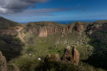 View of the mountainous landscape of volcanic origin along with lots of trees and vegetation and on the horizon, you can see the setting moon Gran Canary island