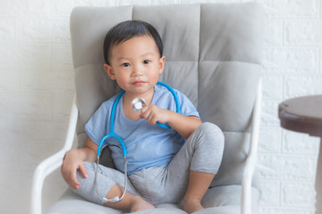 Little boy playing a doctor, children play doctor and hospital using stethoscope, having fun at home or preschool,Tool doctor,Smiling little boy sitting on chair isolated.
