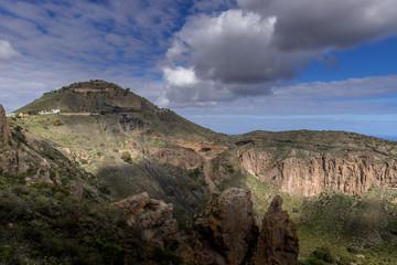 View of the mountainous landscape of volcanic origin along with lots of trees and vegetation and on the horizon, you can see the setting moon Gran Canary island