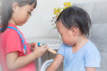 Little girl playing a doctor,boy and girl playing doctor and patient isolated,Two children play doctor and hospital using stethoscope,Sister and brother having fun at home or preschool,Tool doctor.