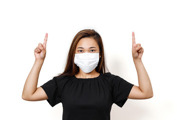 Plain white background with asian lady wearing face mask for prevention of spreading the coronavirus. Two fingers pointing upward space for text.