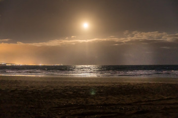 A moon rising above the surface of the ocean that throws reflections on the water levels captured...