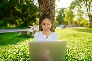 A woman sitting on a lawn with a laptop that works outdoors at home,