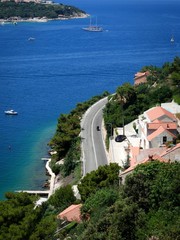 Winding road at the azure coast of Croatia, man on a motorbike.