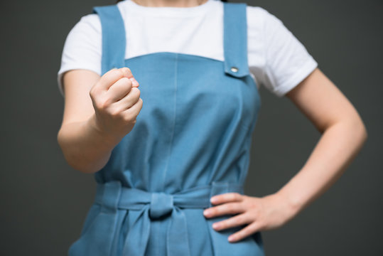 Angry Woman In Blue Dress Is Shaking Her Fist Close Up On Gray Background.