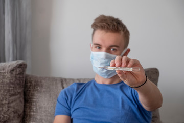 Young caucasian man holding a thermometer. Quarantine. Stop coronavirus