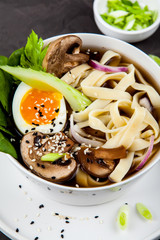 Traditional asian noodle soup pho in bowl, garnished with egg, mushrooms on concrete background. Asian food concept.