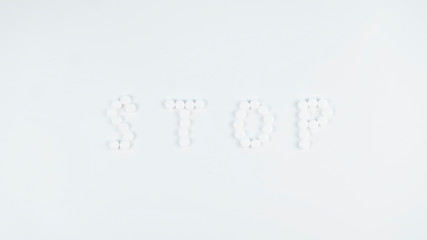 The word STOP written with  pills on white background. Stop Coronavirus concept.