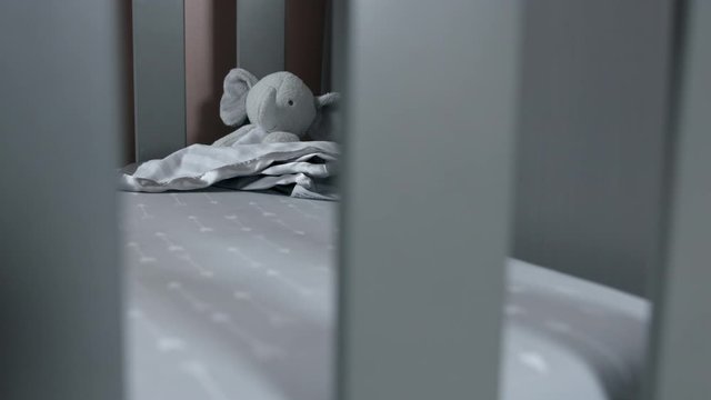 Still shot of a toy elephant sitting in a baby crib