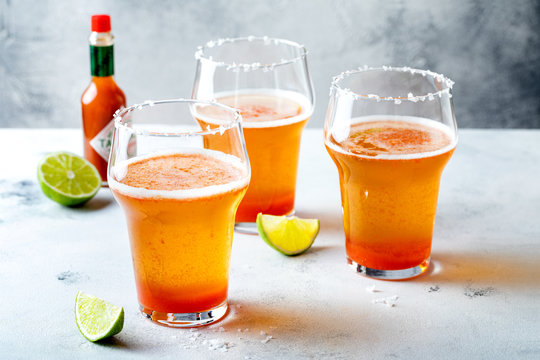 Latin american beer drink Michelada with salt rim and spicy tomato juice. Summer alcohol cocktail michelada or Mexican bloody beer.