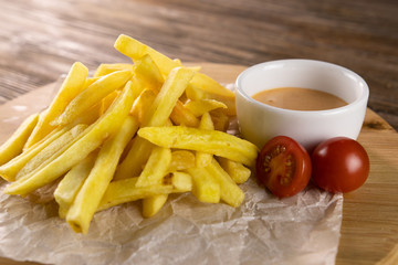 Fried potato with tomato sauce on paper, circle board and wooden table 