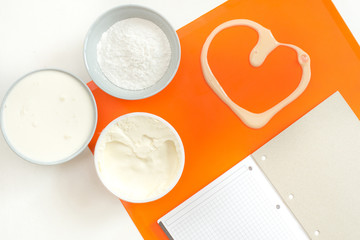 recipe step by step layout of products for cream on a silicone orange mat mascarpone cream for baking powdered sugar top view